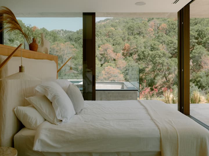 Dormitorio principal con cama tamaño queen, ubicado para disfrutar de vistas a la montaña y al mar. La habitación se abre directamente a una terraza privada. Además, está justo al lado del área del jacuzzi.