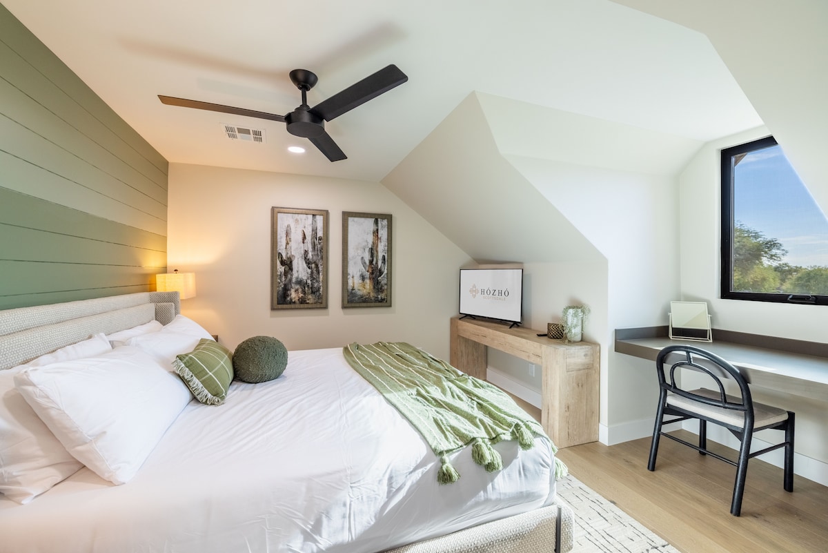 Dormitorio King 9 con baño dedicado: acogedor refugio en el dormitorio con pared verde, muebles modernos y un espacio de trabajo incorporado con vistas a la luz natural.