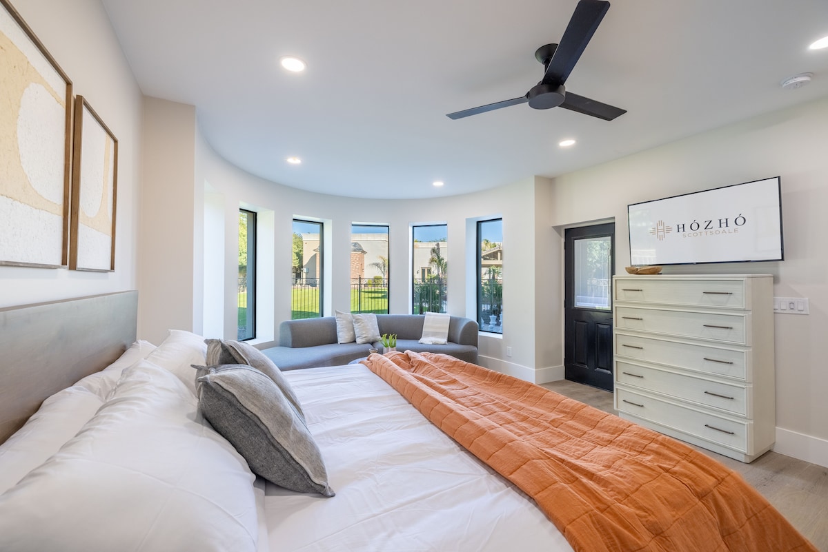 Dormitorio King 4 con baño privado: dormitorio redondo único con ventanas panorámicas, acogedora sala de estar y acceso directo al patio.