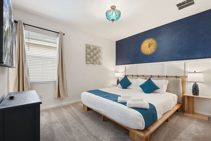 Elegante dormitorio con una moderna cama acentuada en madera, una decoración azul atrevida e iluminación cálida.