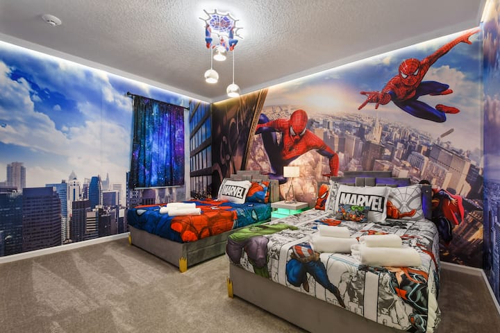 Dormitorio con temática de superhéroes con arte mural atrevido, acogedoras camas individuales y vistas inmersivas a la ciudad.
