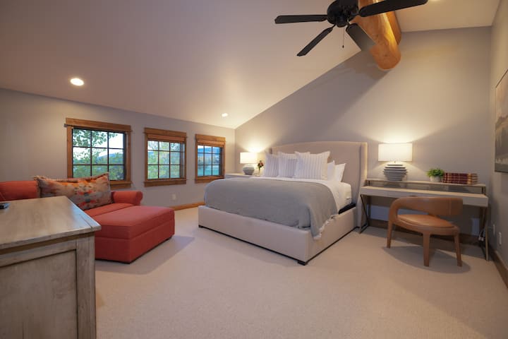 Unwind in your spacious bedroom retreat with soaring ceilings and warm wood beams. Sink into the plush king bed or curl up on the cozy seating area while enjoying treetop views through charming windows.