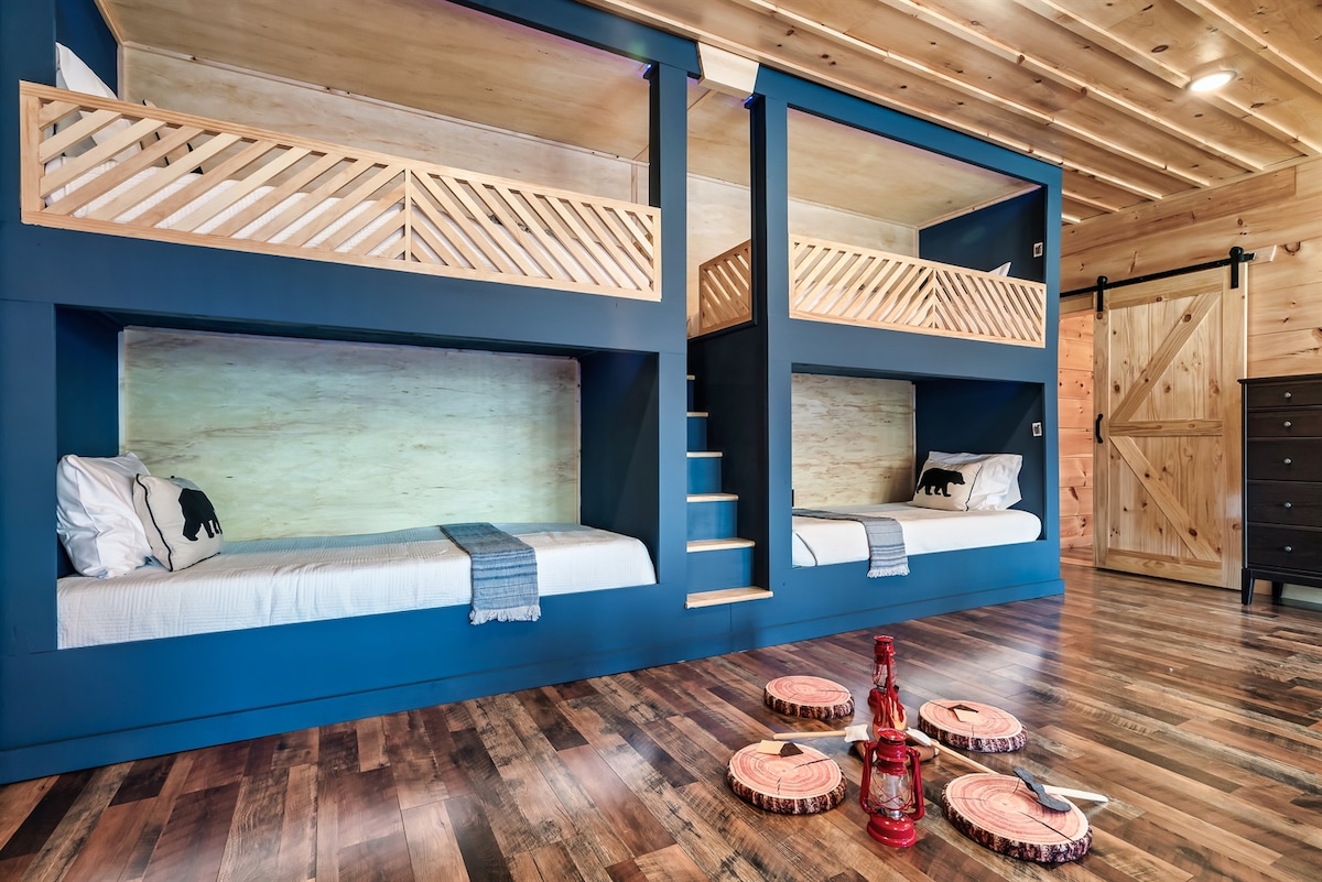 صالة الطابق السفلي: منطقة نوم مخصصة مع سريرين XL بطابقين مصنوعين حسب الطلب، وأضواء مميزة ومخرج لكل سرير، ومدخل جاك وجيل، وتلفزيون ذكي 65 بوصة، وخزانة ملابس