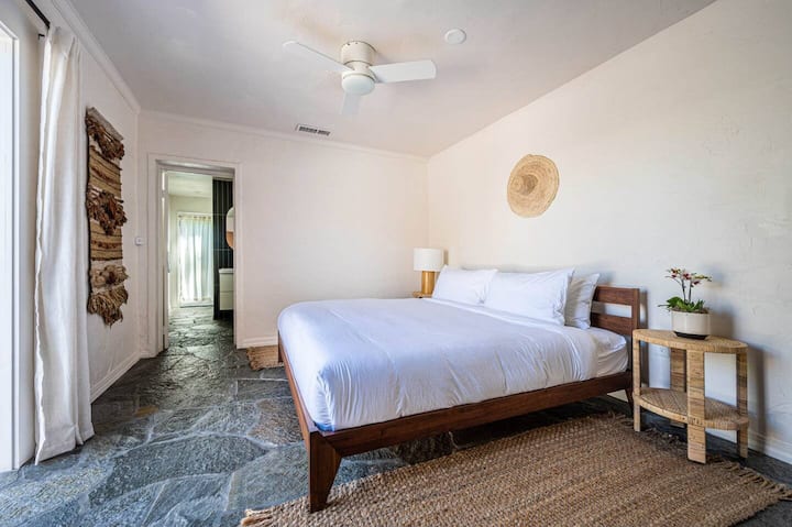 主卧室明亮通风，配有舒适的床上用品，散发着沙漠的魅力。