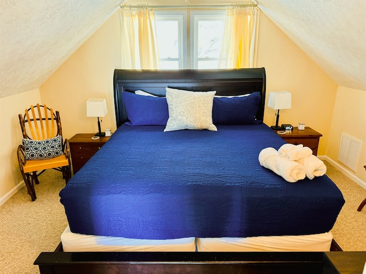The Top Floor King Bedroom has 2 nightstands, charging outlets with USB ports, luggage racks, a closet to hang clothes, a chair to sit and rest, as well as a Roku Smart TV.