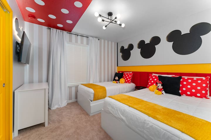 Táto veselá spálňa je svetlá a príjemná, s dvoma útulnými posteľami so žiarivými žltými prikrývkami a hravým dekorom Mickey Mouse, a to všetko pod výrazným červeným stropom so zábavnými bodkami, vďaka čomu je ideálna na nezabudnuteľný pobyt.