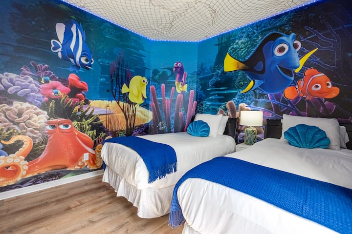 Cameretta colorata per bambini con letti singoli e murales subacqueo
