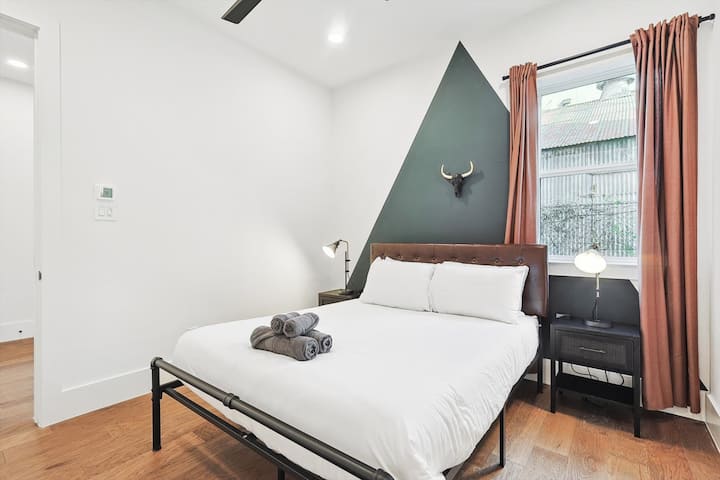 Con una hermosa pared triangular y una decoración sureña, la cama tamaño queen de este dormitorio ofrece un refugio rústico para tu hermoso sueño nocturno.