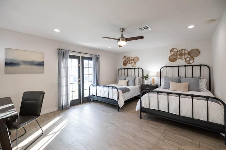 卧室1，配备2张标准双人床、套房浴室、直达后院、电视和书桌。