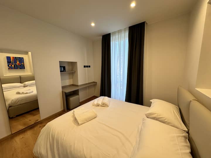 Chumba cha kulala kilicho na kitanda cha watu wawili, kioo, meza ya koni na kabati lililo wazi