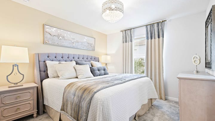 Charmante slaapkamer met zachte neutrale kleuren, een getuft hoofdeinde en een prachtige kroonluchter!