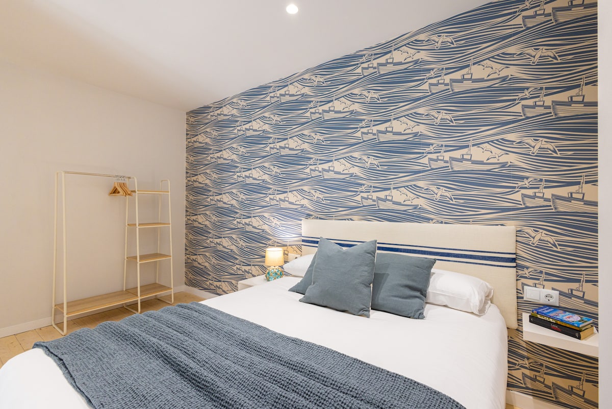 Prostrana spavaća soba s bračnim krevetom, uređena u plavim tonovima koji podsjećaju na more, stvarajući atmosferu mira i opuštanja