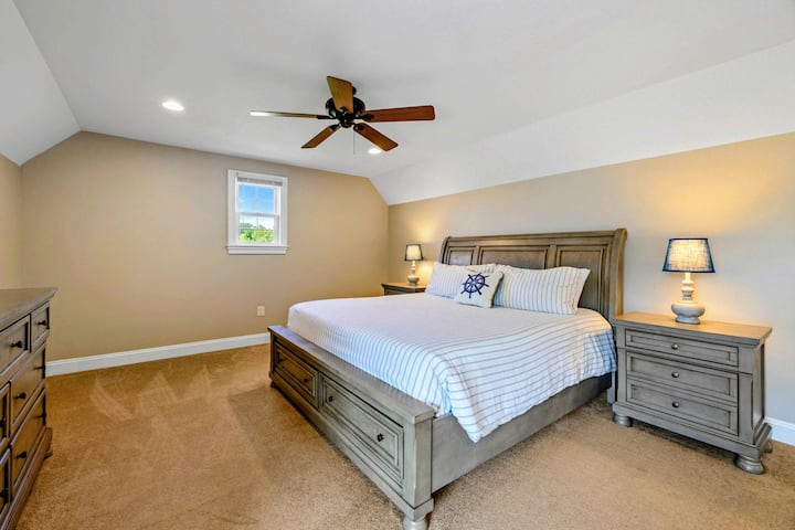 Suite Superior: una cama king con ropa de cama de estilo náutico, techo abovedado y un asiento junto a la ventana con vista al jardín.