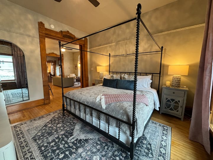 Priestranná hlavná spálňa s nádhernou posteľou s nebesami, teplým ambientným osvetlením a očarujúcimi historickými detailmi pre útulný, ale elegantný odpočinok.