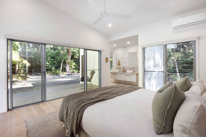 Drift off in the primary bedroom's king bed with leafy views, direct access to the outdoors and cooling comfort from both air-conditioning and ceiling fans.