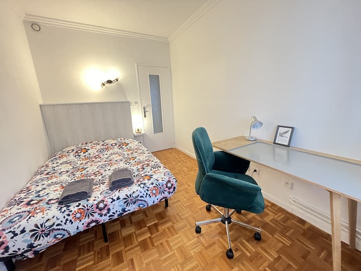 Priestor na spanie s manželskou posteľou a písacím stolom.