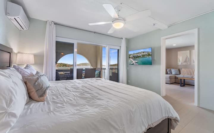 De primaire slaapkamer met kingsize bed, eigen badkamer, koude airconditioning, een flatscreen-tv en toegang tot het balkon.