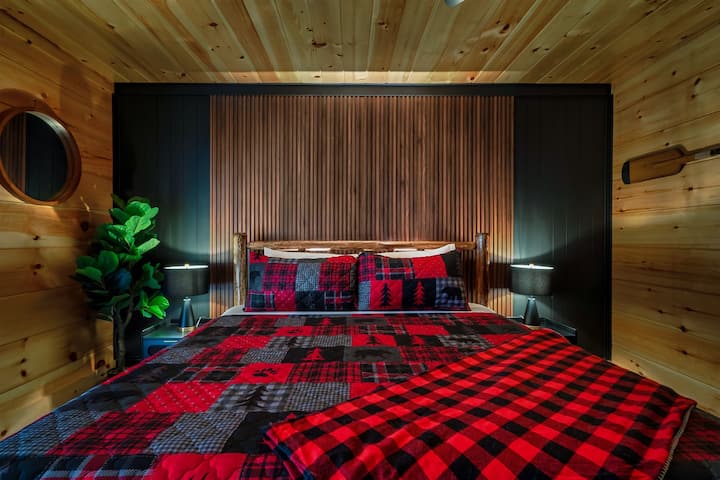 暗い木製のアクセントの壁があるマスターベッドルームの親密な環境。