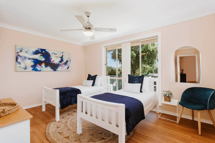 El sexto dormitorio cuenta con dos camas individuales, que transmiten luz natural y una acogedora silla de lectura con acceso al patio trasero. 