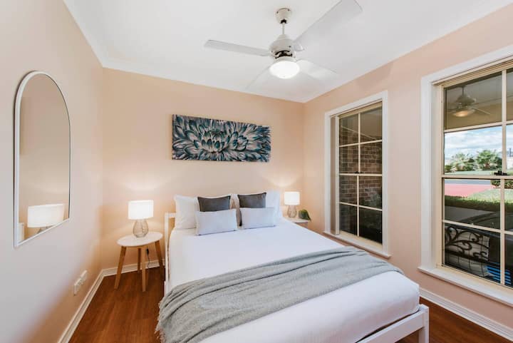 El segundo dormitorio cuenta con una acogedora cama tamaño queen, bañada de luz natural desde las altas ventanas que dan a los jardines delanteros cuidados. Disfruta de las vistas o baja las persianas para disfrutar de la sombra y la privacidad.