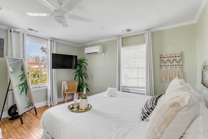 Chambre 1 : lumineuse et spacieuse avec un lit king size, une télévision, la climatisation et de grandes fenêtres.