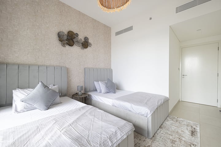 ห้องนอนที่เงียบสงบมีเตียงแฝดโทนสีเทานวลและการตกแต่งผนังอย่างมีสไตล์เพื่อการพักผ่อนที่ผ่อนคลาย