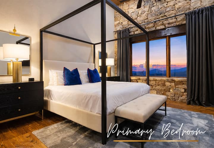 Un lujoso dormitorio tamaño king con una cama con dosel, sábanas suaves y grandes ventanales que ofrecen vistas serenas a la montaña. (Nivel principal)