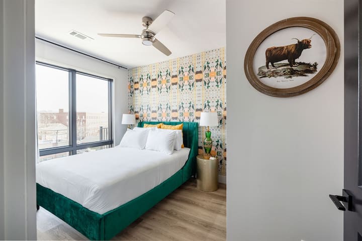 Queen bedroom featuring custom wallpaper, blackout shades, and smart TV with YouTube TV