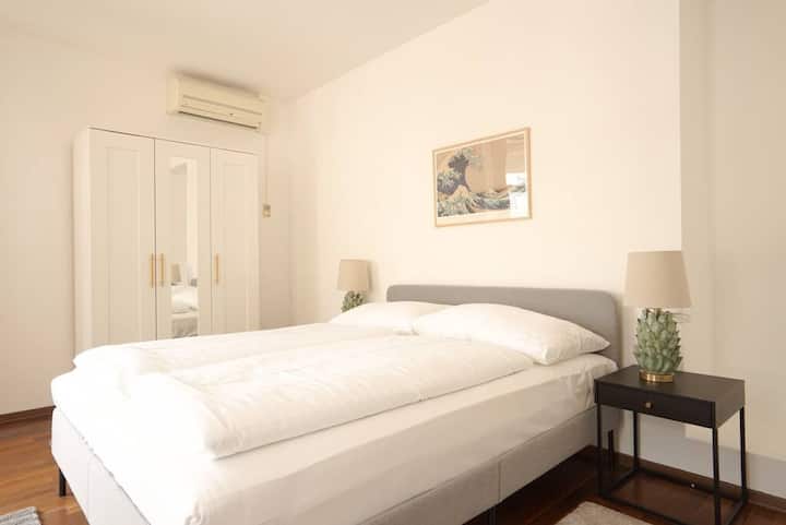 חדר שינה אלגנטי עם מיטה זוגית גדולה, עם צבעים מרגיעים וטקסטיל קטיפתי. הוא מציע מקום מקלט מושלם למנוחה ורוגע. 