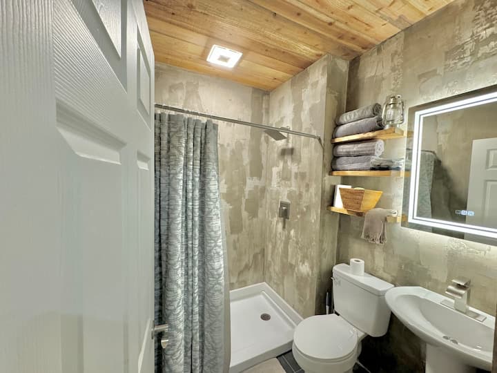 Ervaar urban chic in deze strakke betonnen badkamer, compleet met een chique spiegel met achtergrondverlichting die een vleugje sfeer toevoegt aan je ochtendroutine. Stap in een ruimte waar modern design en ontspanning samenkomen en de ultieme coole vibes voor je verblijf bieden.