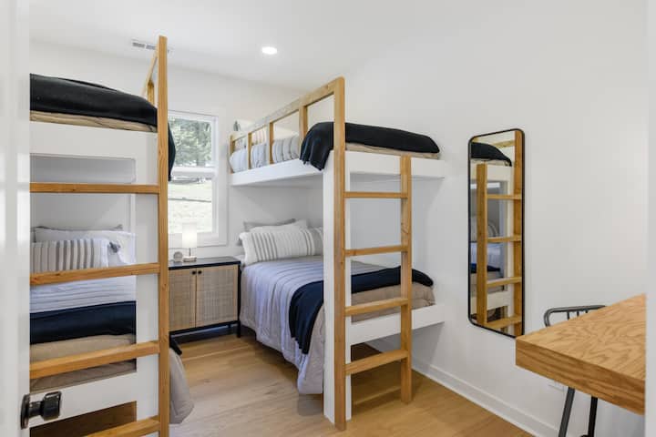 Dormitorio #5 queen sobre cama tamaño queen y dos camas individuales sobre literas integradas, con acceso a un baño compartido con bañera/ducha.