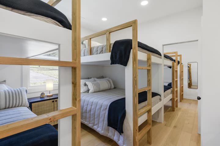 Dormitorio #4 queen sobre cama tamaño queen y dos camas individuales sobre literas integradas, con acceso a un baño compartido con bañera/ducha.