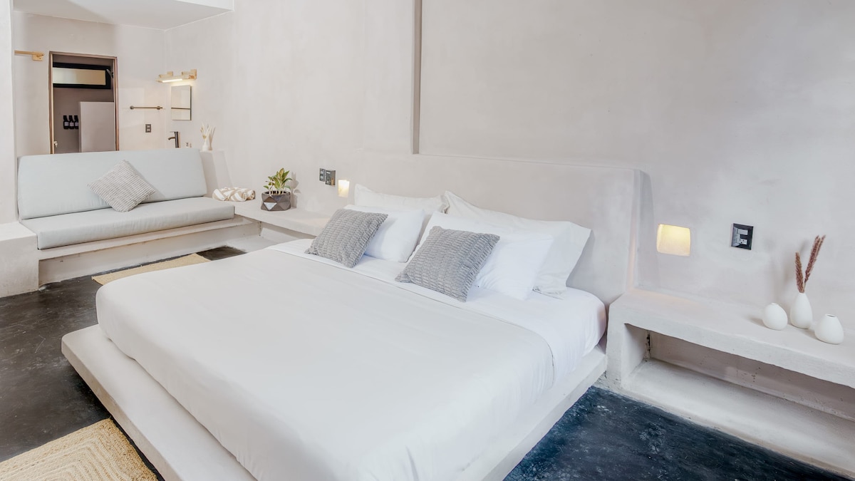 Entra en el espacioso lujo del dormitorio principal, con una cama tamaño king vestida con sábanas de primera calidad. Refréscate en el baño privado con una moderna ducha, luego relájate con total comodidad con aire acondicionado y suaves rejillas de ventilación en el techo.