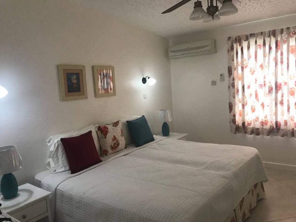 Geräumiges Schlafzimmer mit bequemen Betten und natürlichem Licht, das eine Klimaanlage und einen Deckenventilator für Komfort bietet.