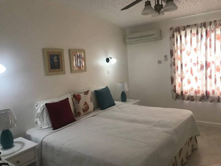 חדר שינה מרווח עם מיטות נוחות ואור טבעי, המציע מיזוג אוויר ומאוורר תקרה לנוחותכם.