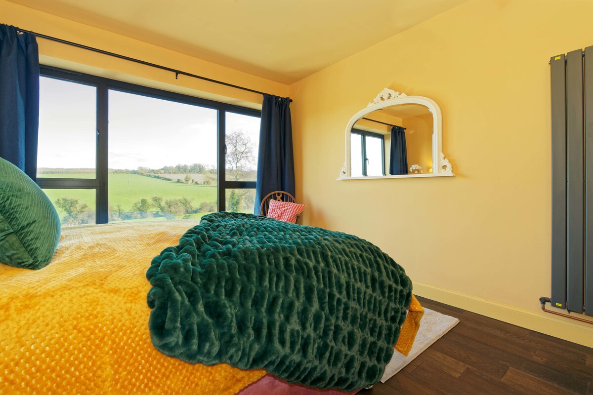 Големи картинни прозорци оформят гледката към древната гора на върха на хълма отвъд голямата градина