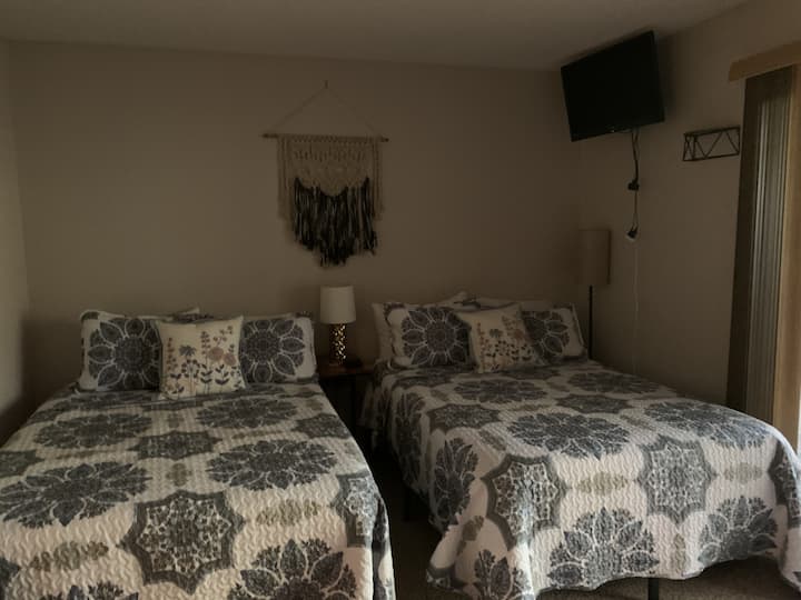 Amplia habitación con dos cómodas camas y un televisor montado, perfecta para familias, amigos o estancias prolongadas.