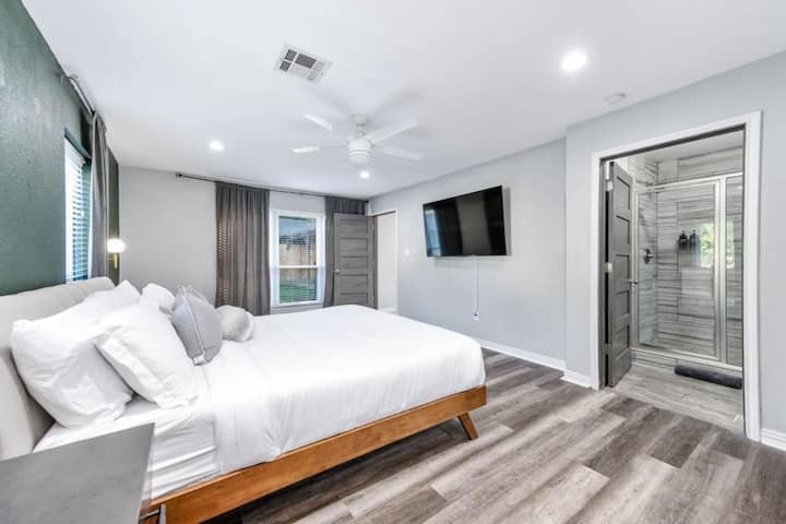 Bedroom retreat with a touch of luxury: TV by the bed, shower nearby.
