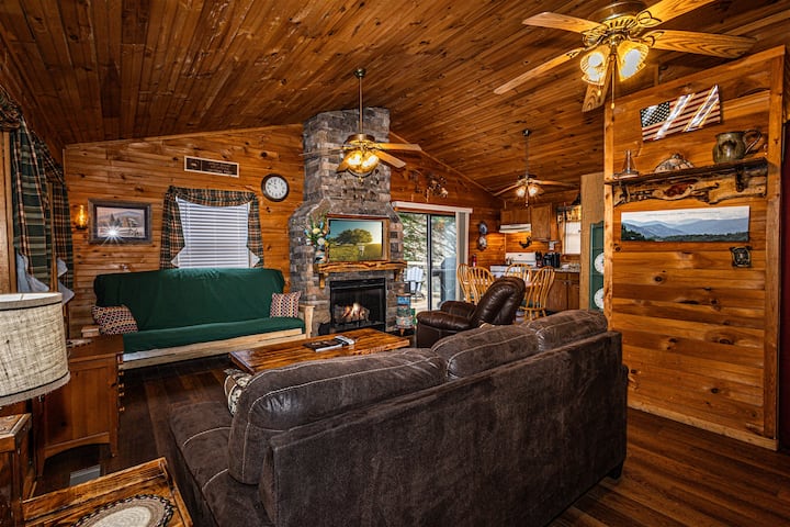 Cozy living room at Blue Mist Mountain Retreat featuring a stone fireplace, rustic wood decor, and plush seating for relaxing nights in.