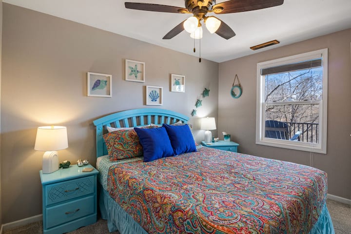 Živá rodinná spálňa s farebnou posteľnou bielizňou, námornou výzdobou a krásnym výhľadom, ideálna na veselý únik pri jazere.