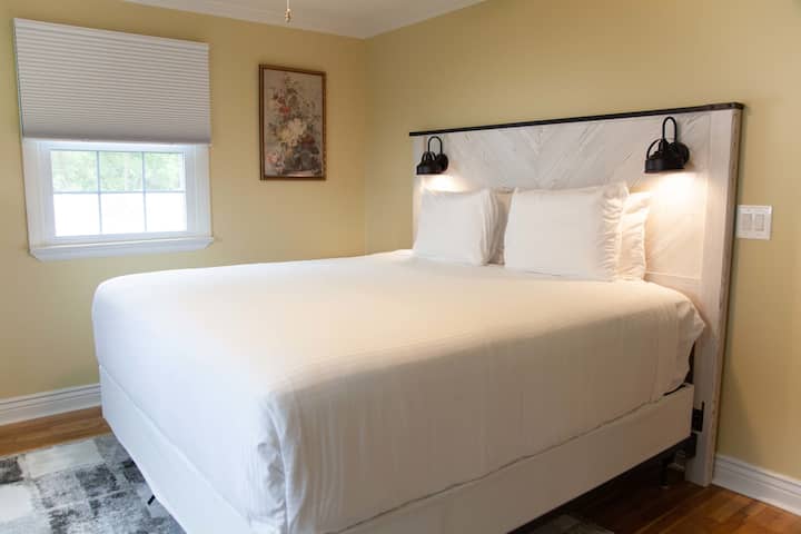 Chambre Queen 1 : literie confortable, lumière naturelle et ambiance paisible.
