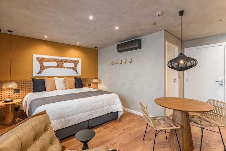 Moderan studio s udobnim dizajnom, istaknut zidom od senfa i ukrasima u neutralnim tonovima. Udoban bračni krevet, drveni stol za blagovanje i viseće svjetiljke stvaraju ugodnu i sofisticiranu atmosferu.