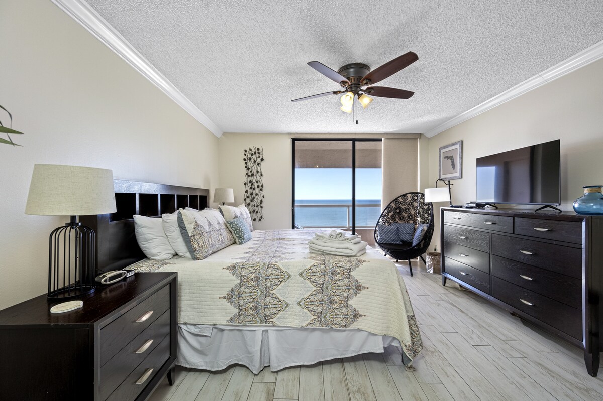 להירגע בחדר שינה ראשי מרווח עם מרפסת פרטית עם נוף שליו לים.