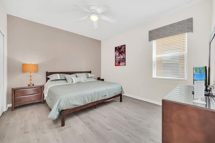 חדר שינה בקומת הקרקע עם מיטת קינג סייז, מאוורר תקרה, טלוויזיה עם מסך שטוח, ארון שקופיות