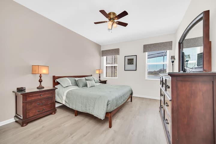 חדר שינה בקומת הקרקע עם מיטת קינג סייז, מאוורר תקרה, טלוויזיה עם מסך שטוח, ארון שקופיות