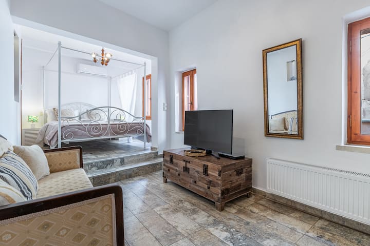 Casa Eleni的卧室提供舒适的度假胜地，配有标准双人床、舒适的沙发和智能电视，供您娱乐。 还设有带浴缸的套内卫生间，提供舒适和放松。