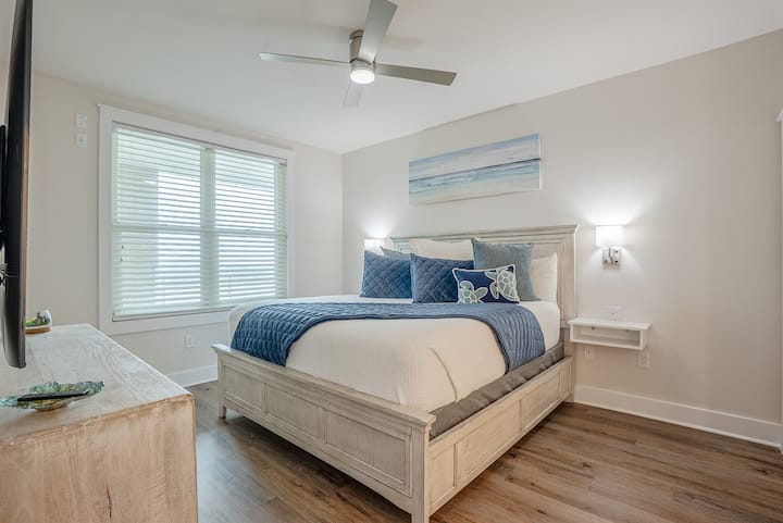 Spacious bedroom with a comfortable king-size bed, soft lighting, and plenty of room to unpack. Large windows bring in natural light and make the space feel open and calm.