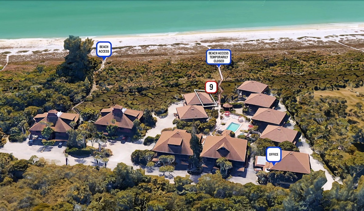 An aerial view illustrates a cluster of charming cottages surrounded by greenery, with a pathway leading to beach access. A swimming pool is visible at the center, framed by the inviting outdoor space, while the serene shoreline lies in the background.