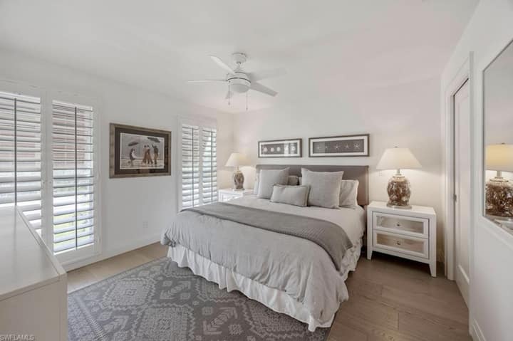 Пространа гостинска спална соба со свежа постелнина и топол крајбрежен стил