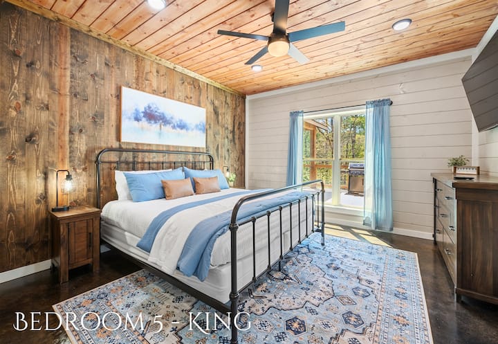 This welcoming King bedroom combines rustic wood paneling with elegant blue textiles and offers direct access to the sunlit outdoors.